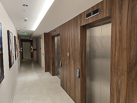 Modern elevator cabin interior, stainless steel details, illuminated control panel, and reflected lights.