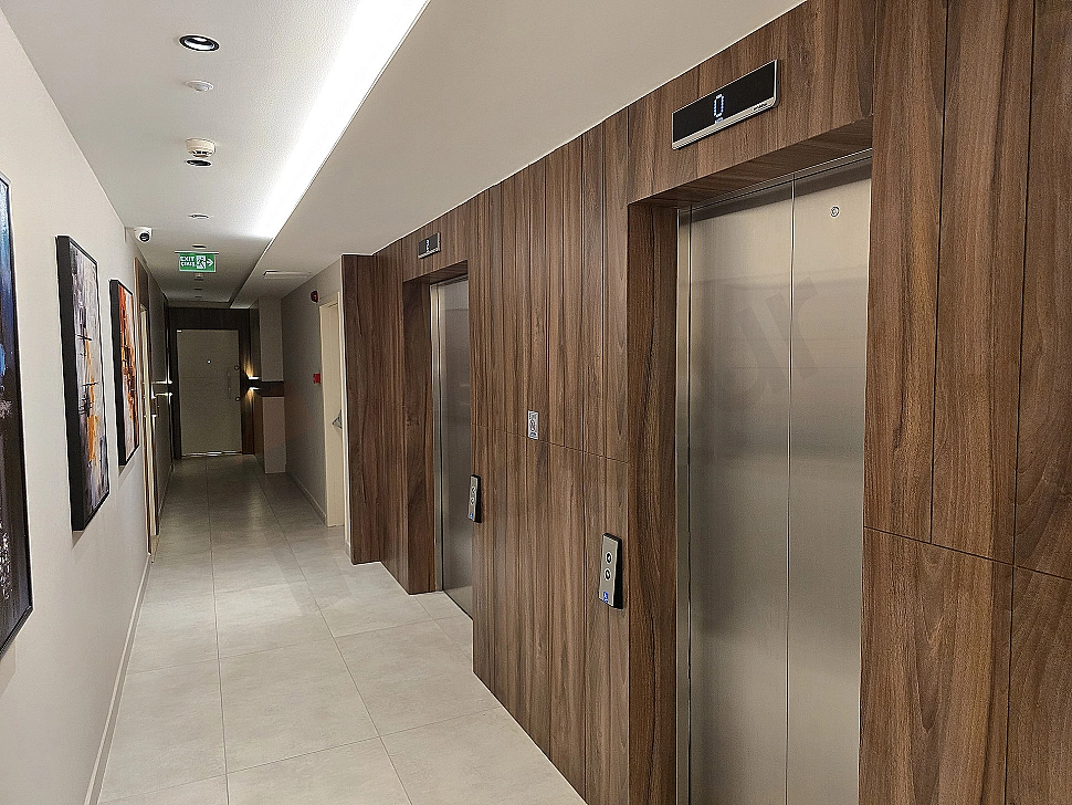 Modern elevator cabin interior, stainless steel details, illuminated control panel, and reflected lights.