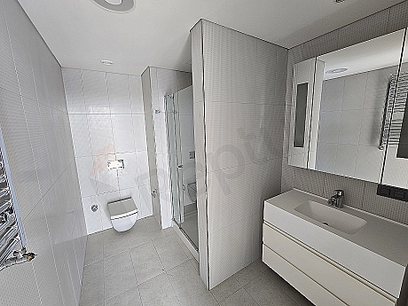Modern designed, bright and spacious bathroom. White ceramics, wooden details and stylish fixtures.