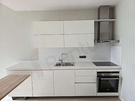 Bright kitchen with modern white cabinets, wooden countertop, and built-in white appliances.