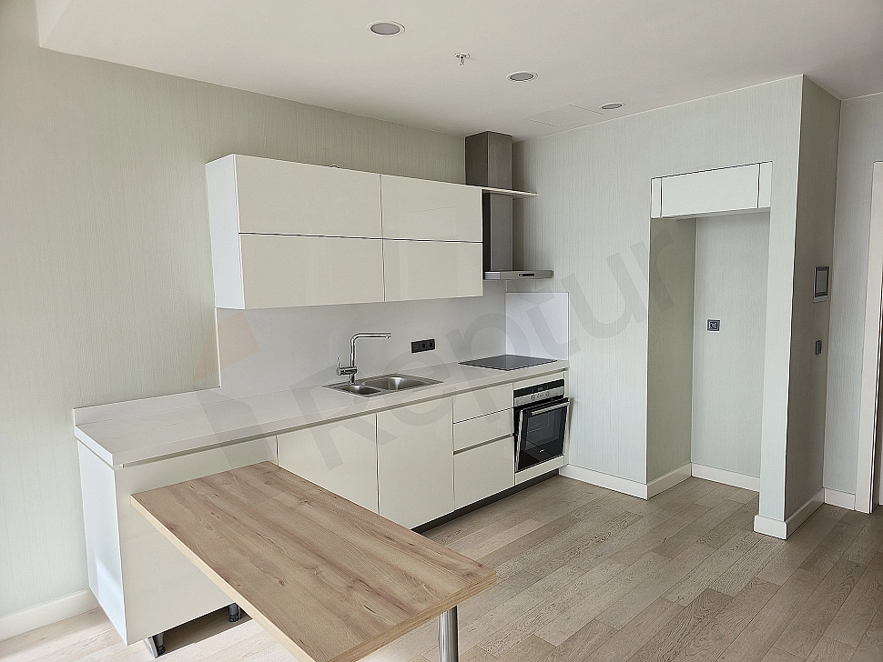 Bright kitchen with modern white cabinets, built-in oven, and hob.