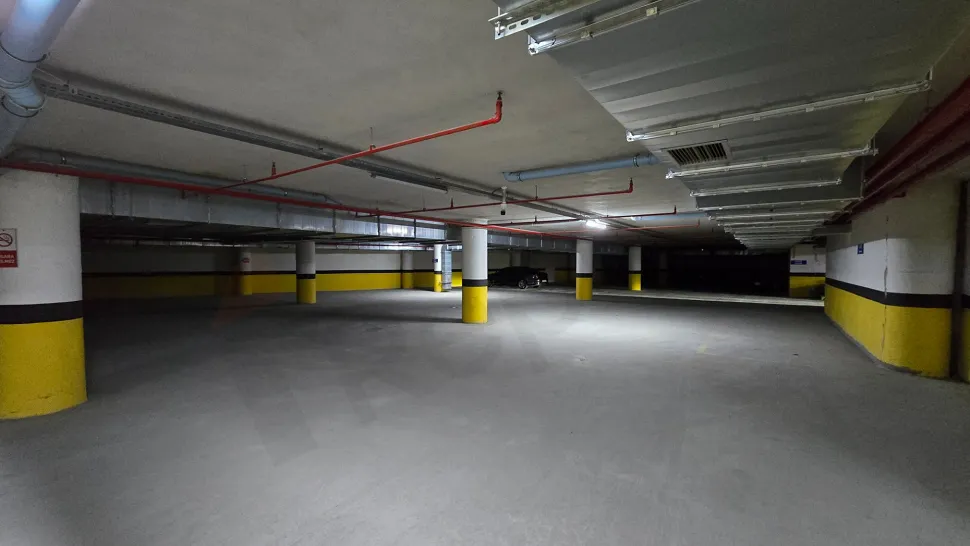 View of a spacious and well-lit indoor parking lot with modern architecture.