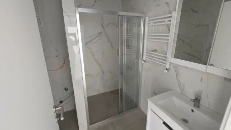 A spacious bathroom interior with modern design and light-colored ceramic tiles.