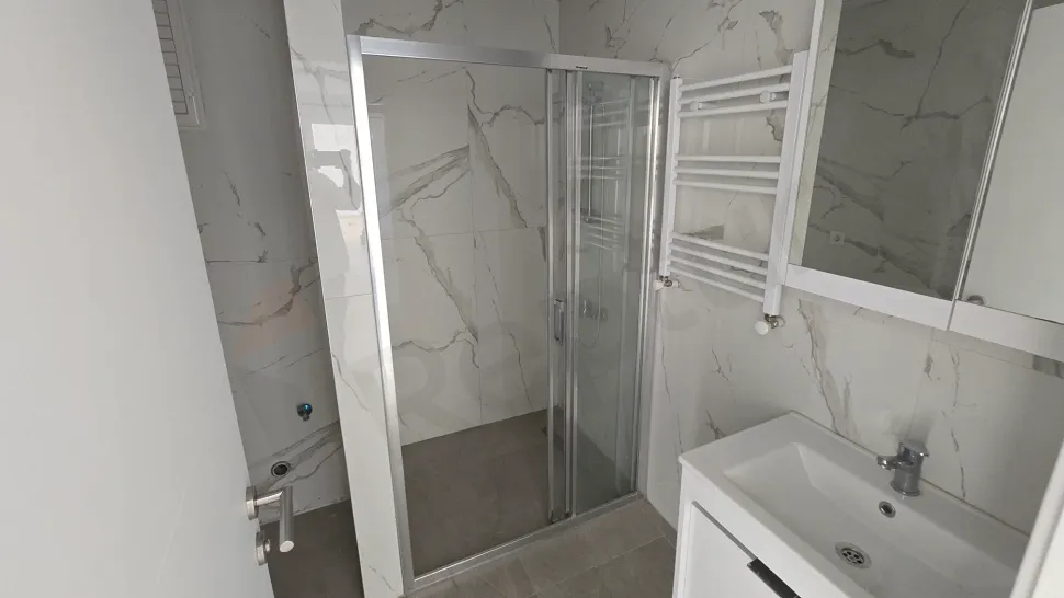 A spacious bathroom interior with modern design and light-colored ceramic tiles.