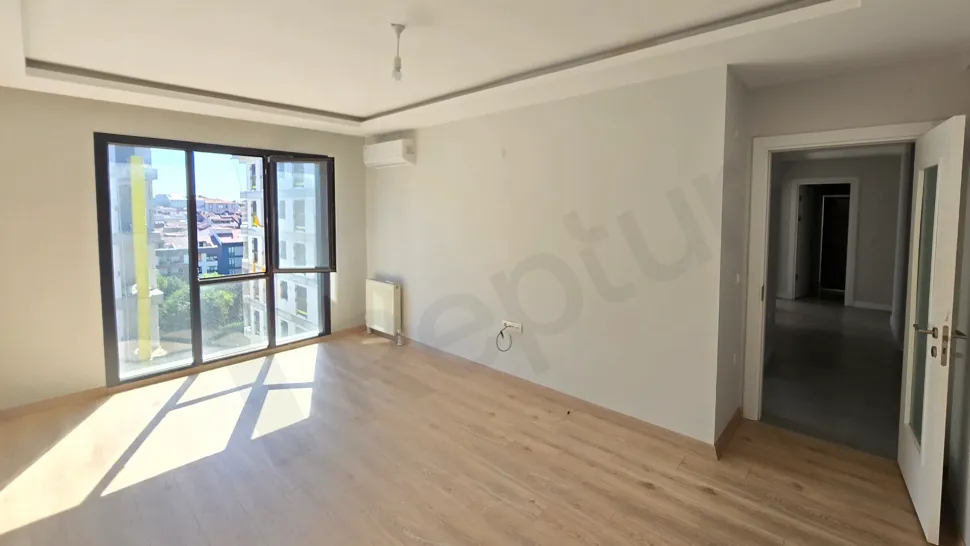 View of a spacious and bright living room area with natural light in a modern apartment.