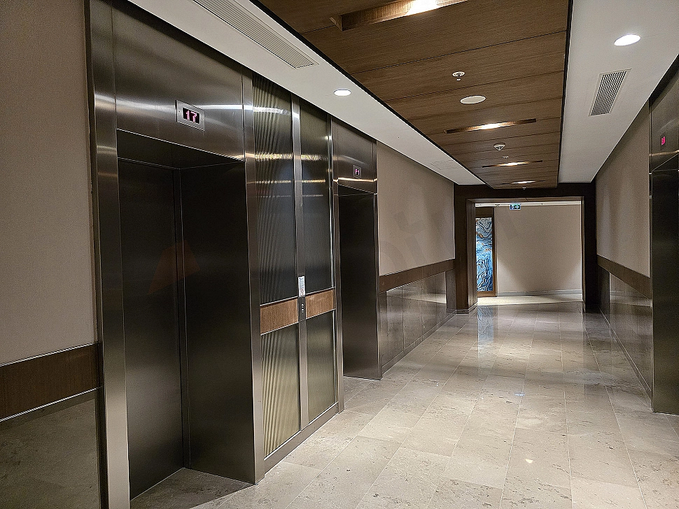 Interior view of a modern elevator cabin. Stainless steel details, lighting and control panel.