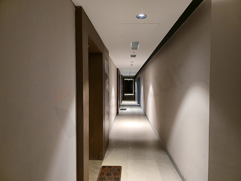 Modern apartment hallway, wooden floor, white walls, built-in closets, lighting details.