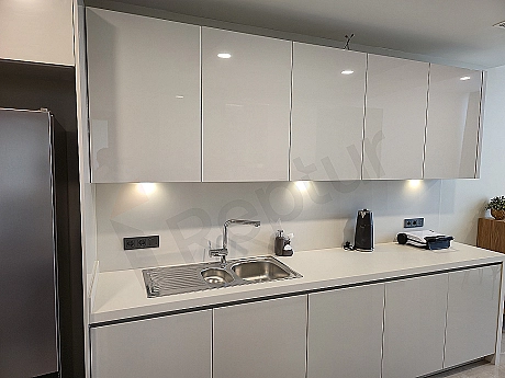 Luxury apartment kitchen with modern white cabinets, built-in appliances, and a large island countertop.