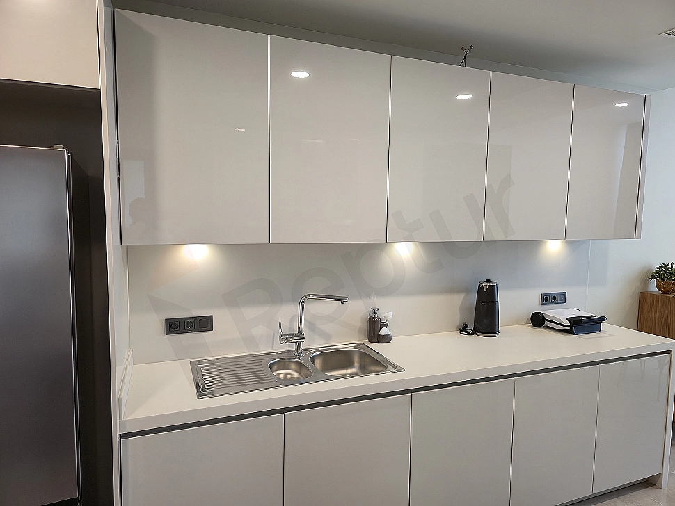 Luxury apartment kitchen with modern white cabinets, built-in appliances, and a large island countertop.