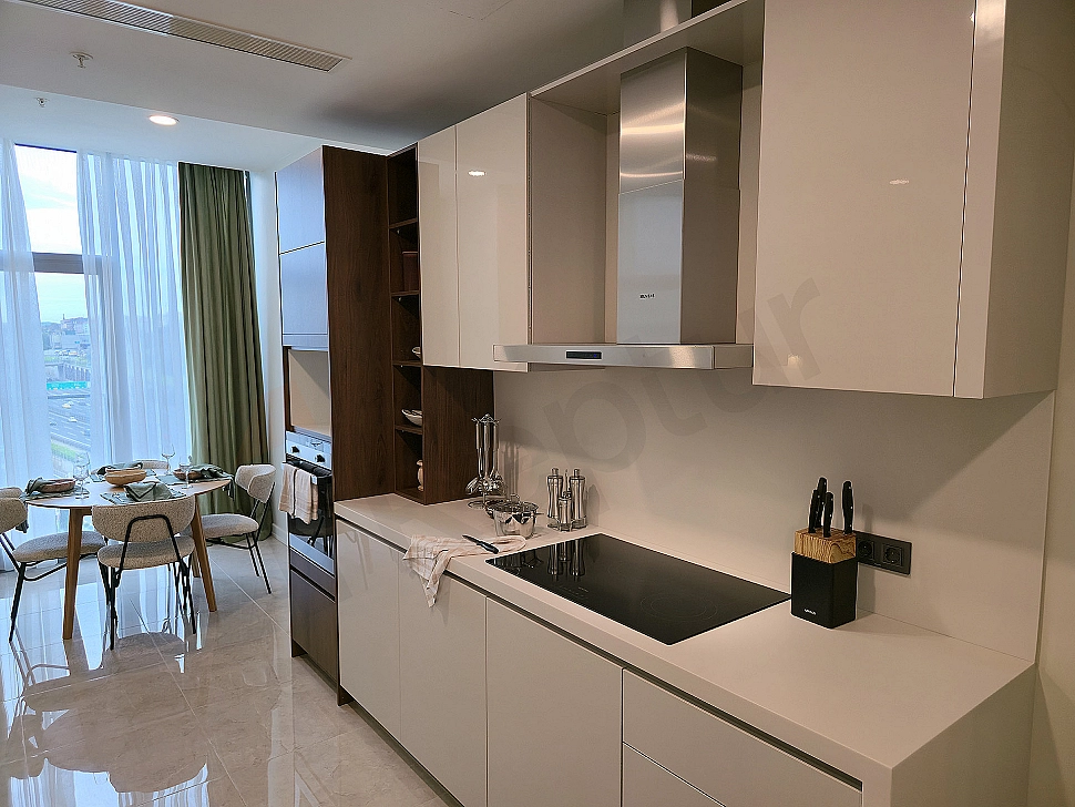 Modernly designed, bright and spacious kitchen with white cabinets and built-in appliances.