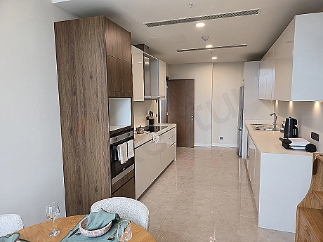 Modern designed, furnished luxury apartment kitchen. Open plan kitchen, island counter, built-in white goods, wooden details.
