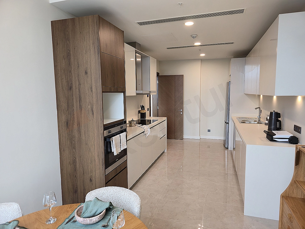 Modern designed, furnished luxury apartment kitchen. Open plan kitchen, island counter, built-in white goods, wooden details.