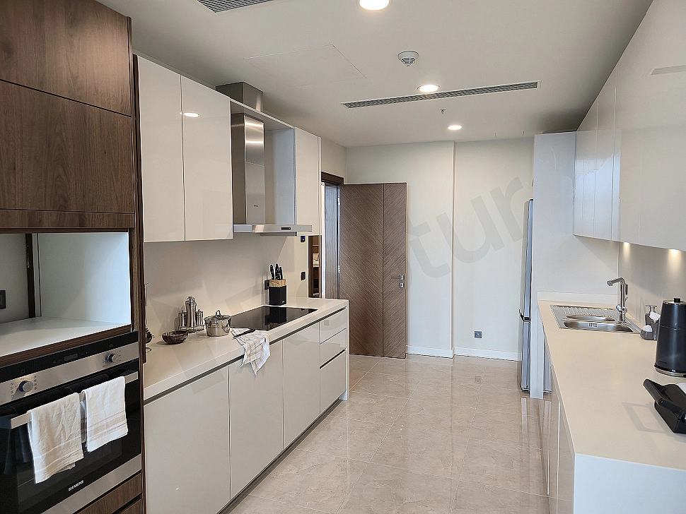 Spacious and bright kitchen with modern white cabinets, built-in oven and stove.