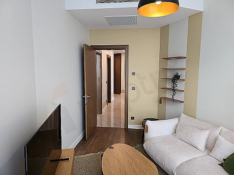 Modern study room: wooden desk, ergonomic chair, bookshelf and city view window.