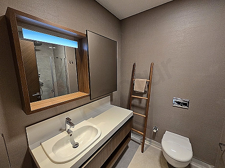 Modern designed, spacious and bright bathroom. Features white ceramics, stylish fixtures, and a large mirror.