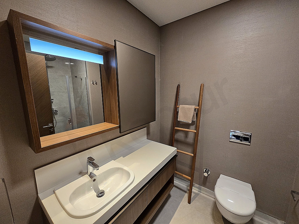 Modern designed, spacious and bright bathroom. Features white ceramics, stylish fixtures, and a large mirror.