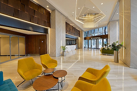 Wide and bright photograph of the modern building entrance. Reception area and stylish seating group are visible at the entrance.