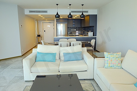 Modern designed, furnished living room. Illuminated by natural light from spacious windows, equipped with comfortable sofa sets and elegant decorative elements.