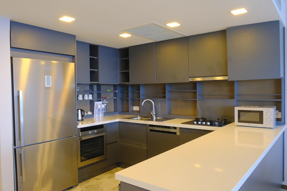 Modern open-plan kitchen featuring white cabinets, a kitchen island, and built-in appliances, creating a spacious and bright living area.