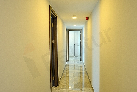 A modern and spacious interior corridor of a luxury apartment. Featuring light-colored walls and a bright ambiance.