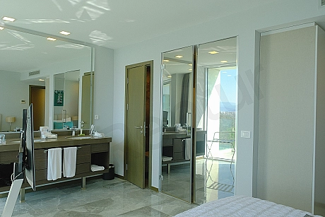 View of a modernly designed, elegantly furnished bedroom. It includes a bed, nightstands, and a window showing the outside.