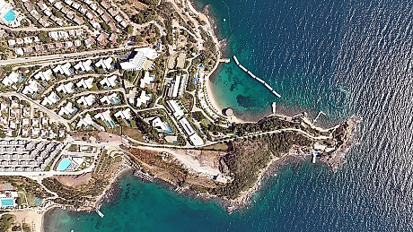 A tranquil beach scene with clear turquoise sea, golden sand, and sun loungers with umbrellas.