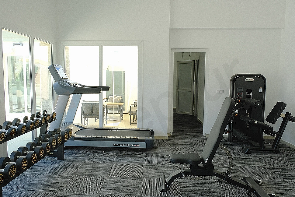 Gym inside a villa, equipped with sports equipment and mirrors.