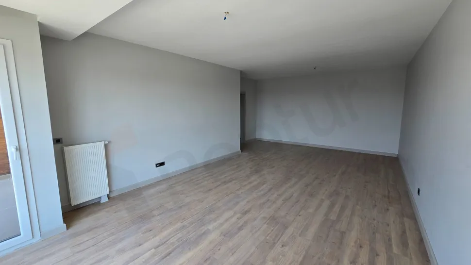 A spacious living room designed with modern architecture, featuring large windows and natural sunlight.