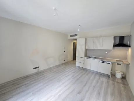 Interior view of a living room in a modern and spacious studio apartment with large windows.