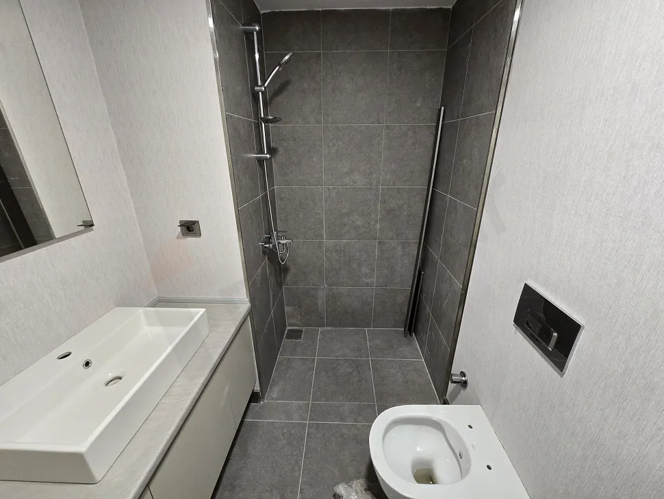 Modern bathroom design with light-colored ceramic tiles and mirror.