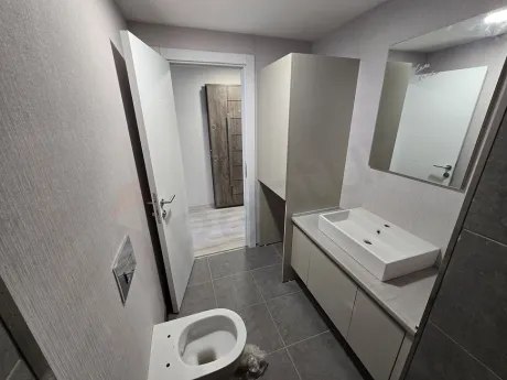 Interior view of a modern bathroom with ceramic tiling, a large mirror, and stylish sanitary ware.