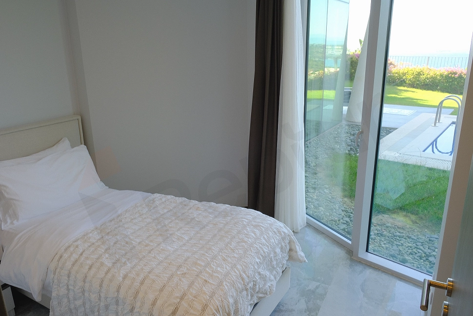 A modern furnished bedroom featuring a large bed, stylish headboard, and bedside tables.