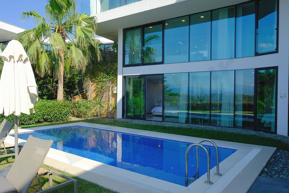 A large outdoor swimming pool with crystal clear blue water located in the garden of a modern residential project.