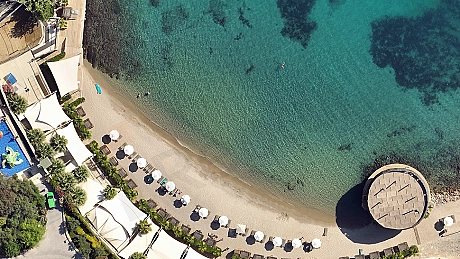 View of a private beach with crystal clear water and sandy shore belonging to a luxury complex in Bodrum.