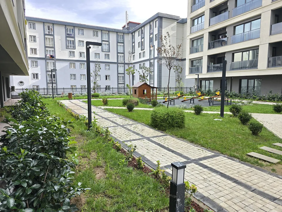 Landscaped green garden area and walking paths of a modern residential complex.