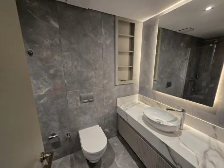 Spacious bathroom area with modern design, stylish washbasin and mirror details.