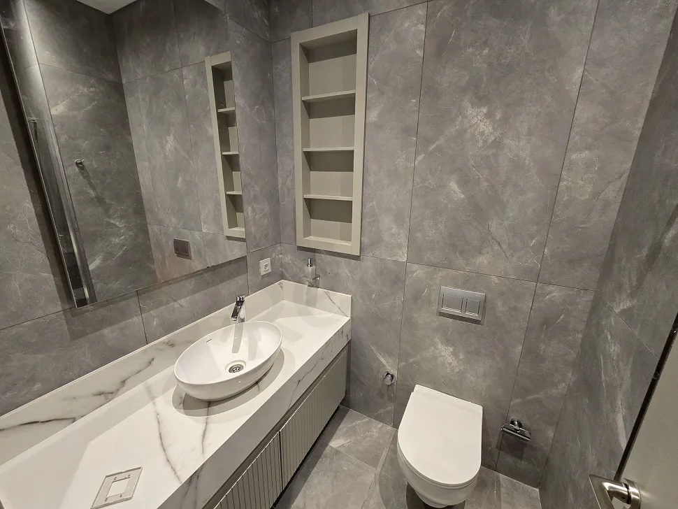 Interior image of a modern bathroom design featuring stylish ceramic tiles, a large mirror, and high-quality bathroom fixtures.