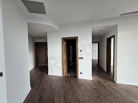 Modern apartment corridor with wooden floor, white walls and built-in closets.