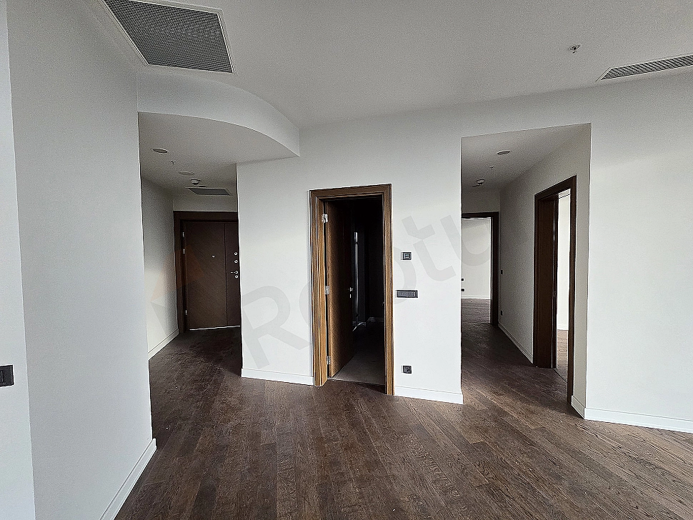 Modern apartment corridor with wooden floor, white walls and built-in closets.