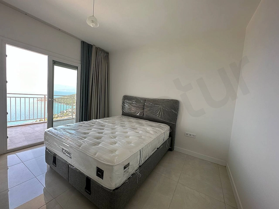 A spacious apartment balcony with sea views and modern furniture in Bodrum.