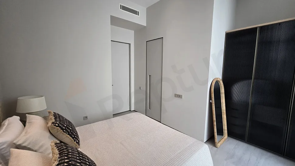 A view of an empty bedroom with modern architecture, large windows, and natural daylight.