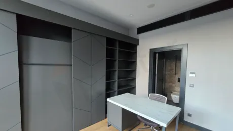 Bright furnished living room interior with modern furniture and large windows.