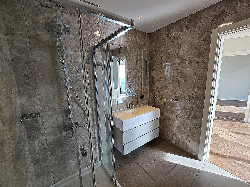 Modern designed, bright and spacious bathroom interior. White ceramics, stylish faucets, and large shower area.