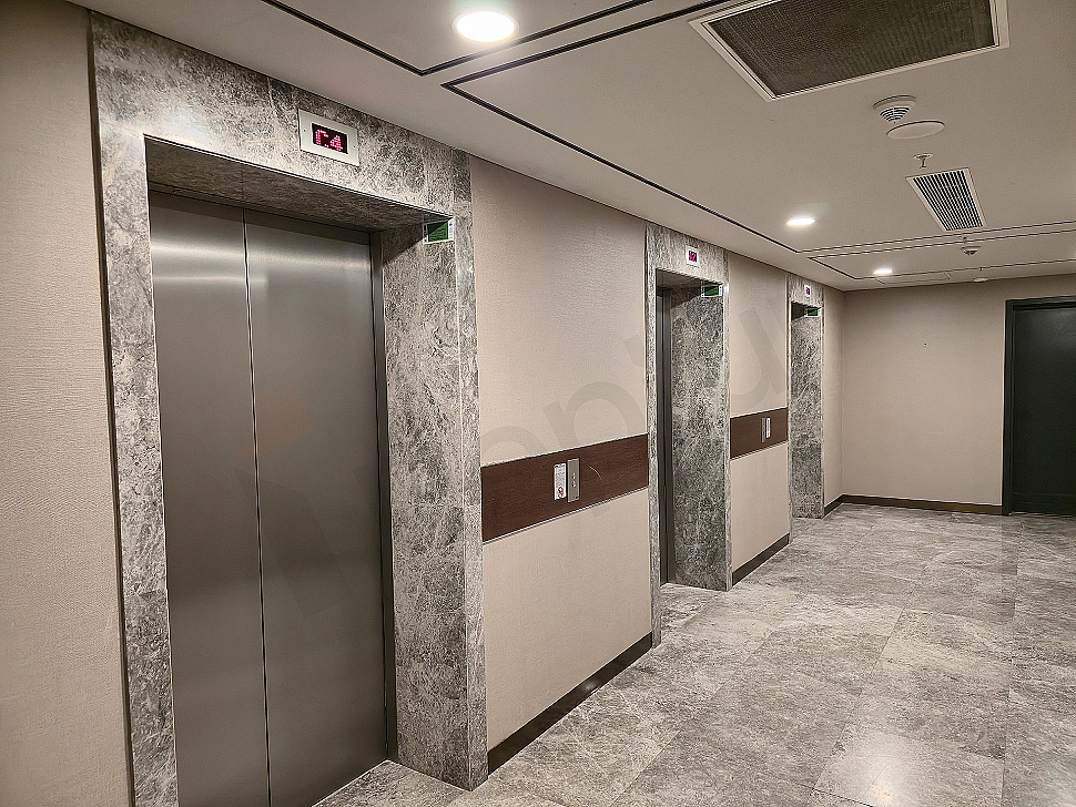 Interior of a modern elevator cabin, stainless steel details, lighting, and control panel.