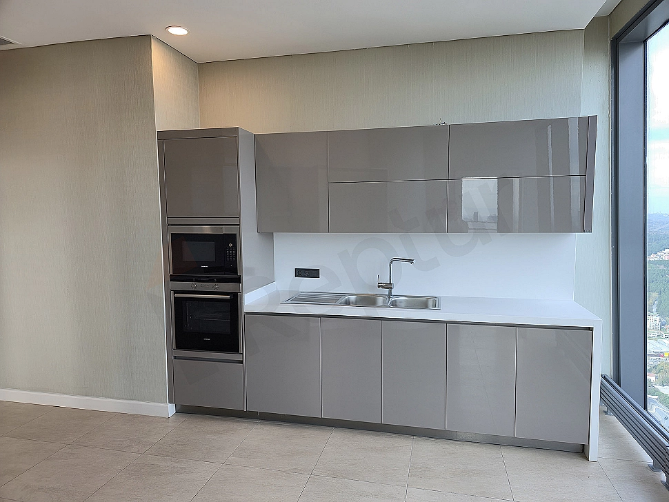 Modern kitchen interior with white cabinets, marble countertops, built-in appliances, and bright design.