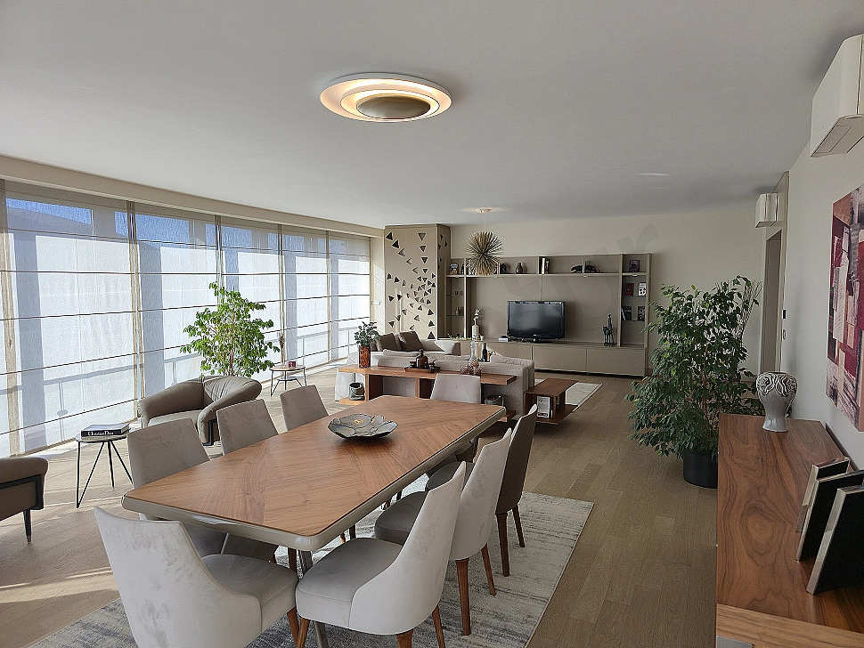 Modernly designed living room with large windows, wooden floors, stylish furniture and city view.