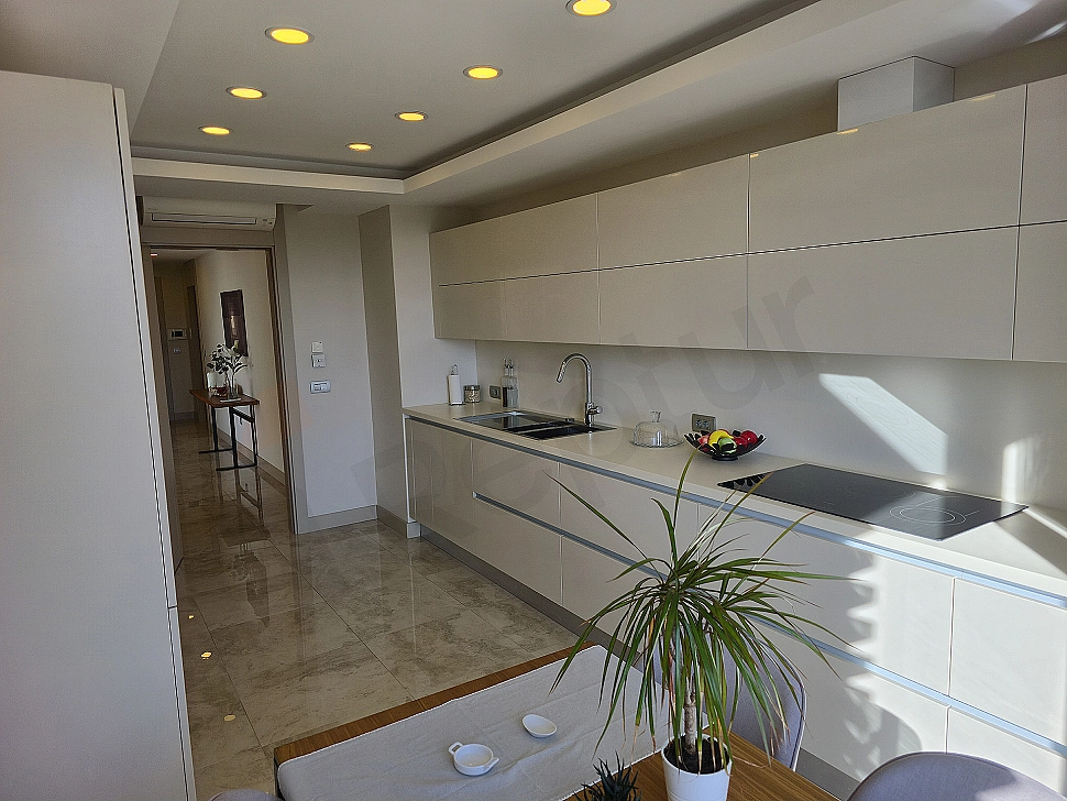 Modern designed, spacious and bright kitchen. White cabinets, marble countertops and built-in appliances.