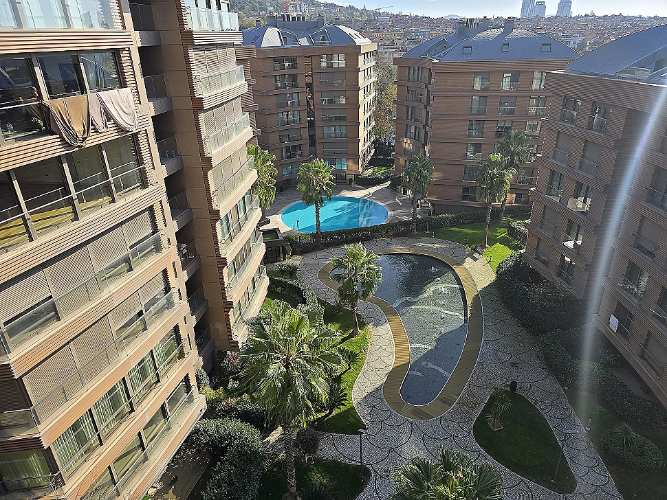 A spacious and well-maintained garden featuring a green lawn, diverse vegetation, and a landscaped seating area.