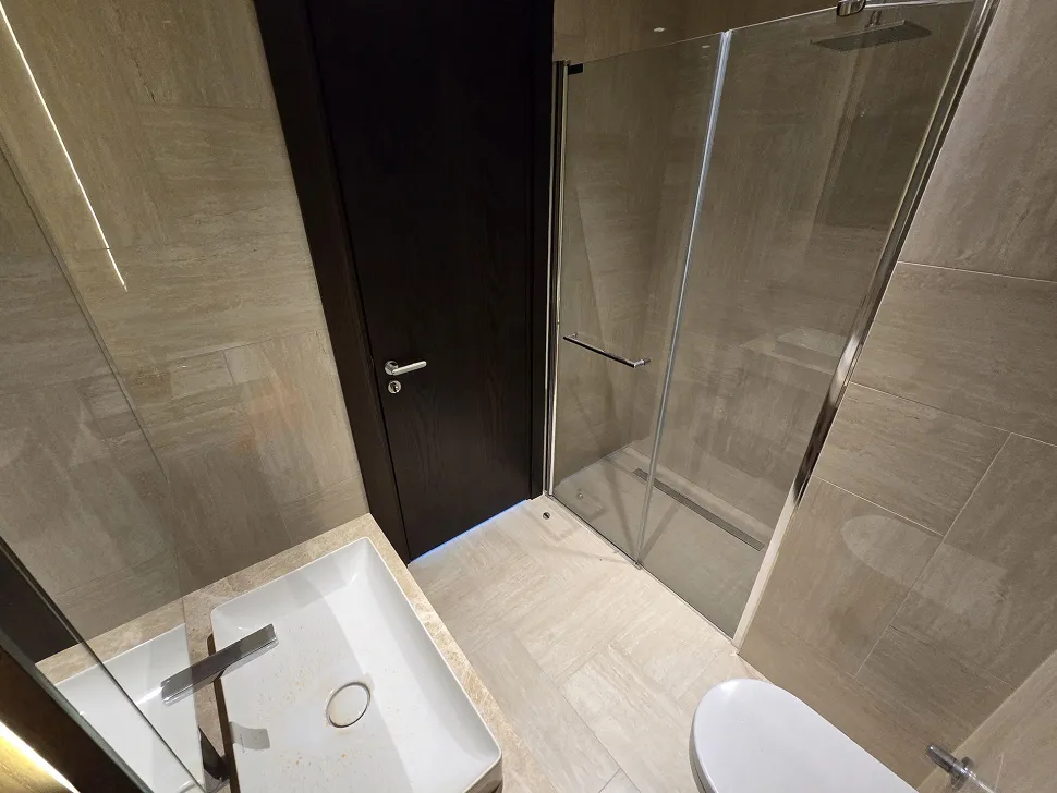 Modern and stylish bathroom with a large mirror and high-quality ceramic tiles.