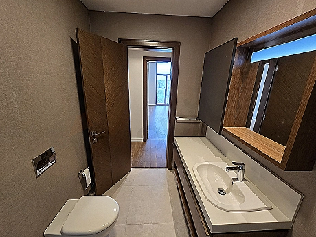 Bright and spacious bathroom with modern design. Featuring white ceramics, stylish fixtures, and a large mirror.